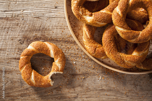 Pile Turkish bagel Simit in a plate  and bitten bagel on wooden background photo