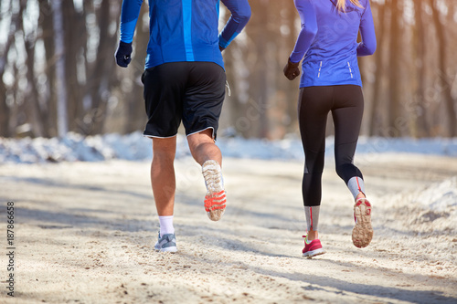 Legs of young athlete while running, back view