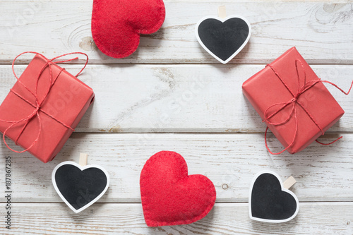 Valentine's card. Red gift boxes, clothespin as heart with space for text on chalkboard on wooden light background. Top view. Copy space.