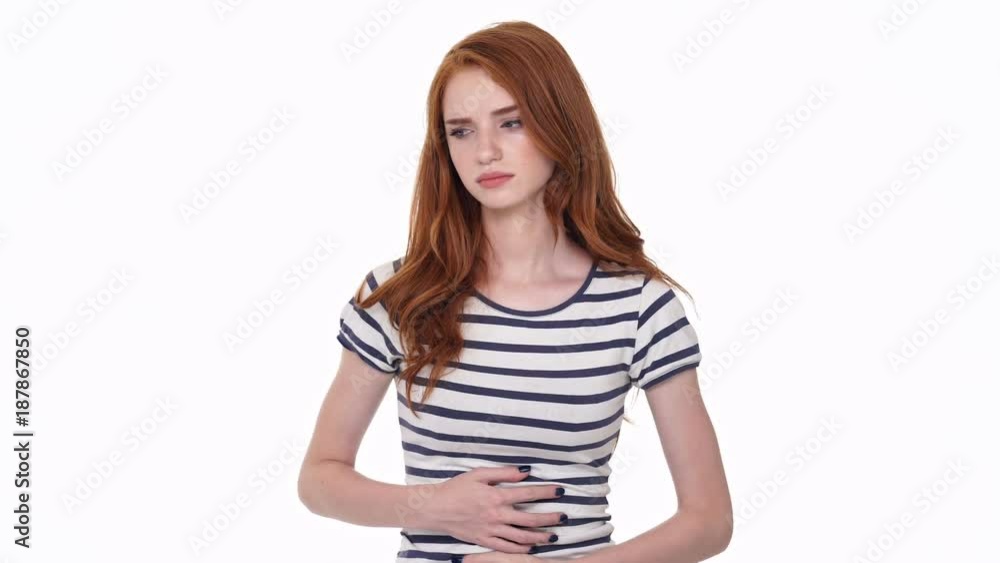 Sad redhead young lady isolated over white wall background have a painful feelings in belly Sad redhead young lady isolated over white wall background have a painful feelings in belly