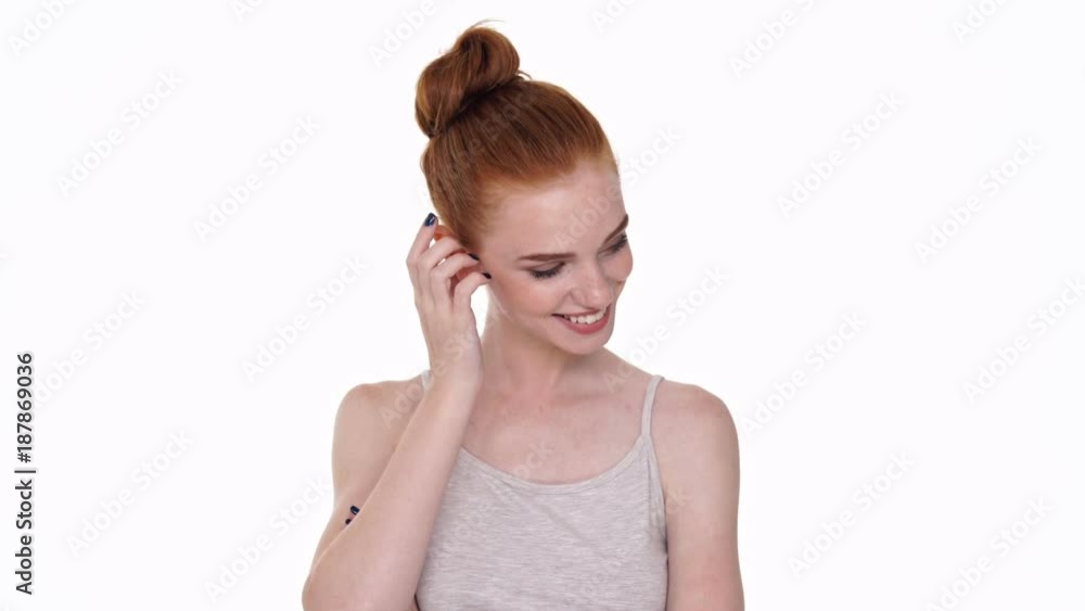 Shy cute young redhead lady looking camera isolated over white wall background Shy cute young redhead lady looking camera isolated over white wall background