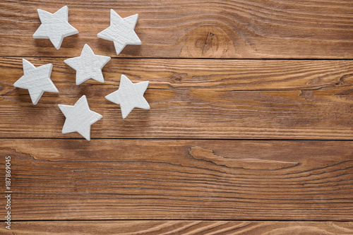 White wooden stars on brown wooden background, copy space, top view.