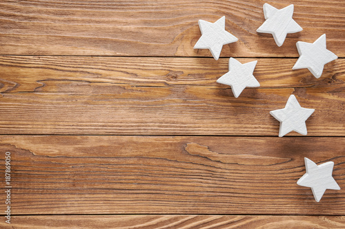 White wooden stars on brown wooden background, copy space, top view.