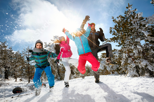 Family with children high jump on winter day on ski vacation and having fun