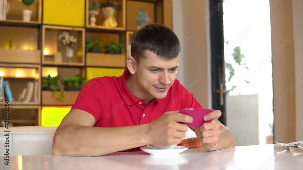 Coffee break. Young man playing game on mobile phone Coffee break. Young man playing game on mobile phone
