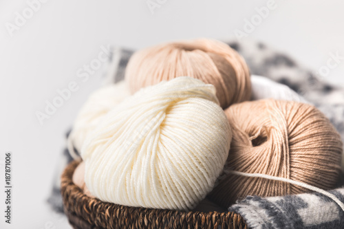 colored yarn balls in wicker basket with blanket isolated on white