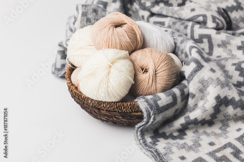 colored yarn balls in wicker basket with blanket isolated on white