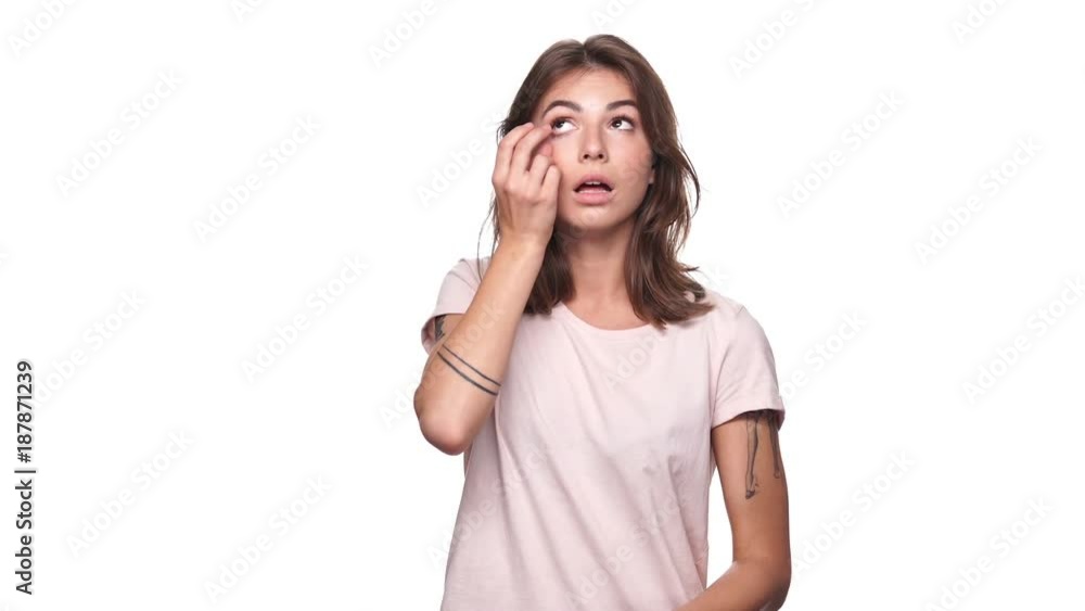 Young brunette woman in t-shirt puts on contact lenses and looking at the camera over white background
Young brunette woman in t-shirt puts on contact lenses and looking at the camera over white background