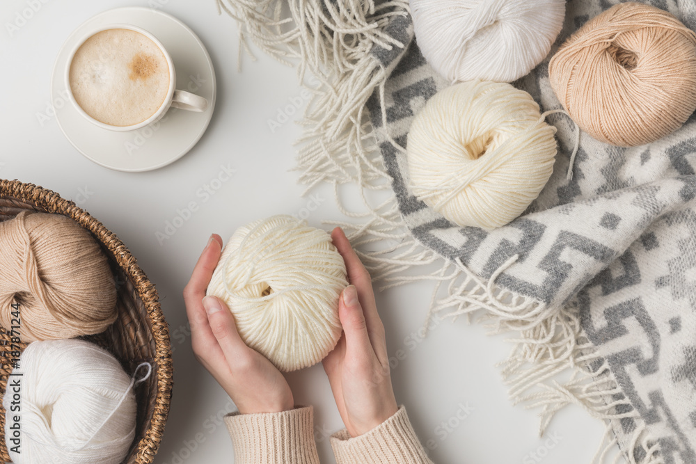 Φωτογραφία cropped view of woman holding cup of coffee and yarn balls on blaket and in bask