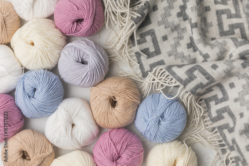 scattered colored yarn balls and blanket on white background