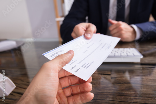 Businessperson Giving Cheque To Colleague photo