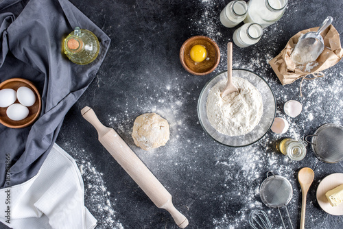 top view of raw dough, baking ingredients and cutlery on marble surface