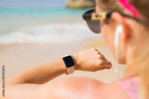 Woman looking at smartwatch on the beach