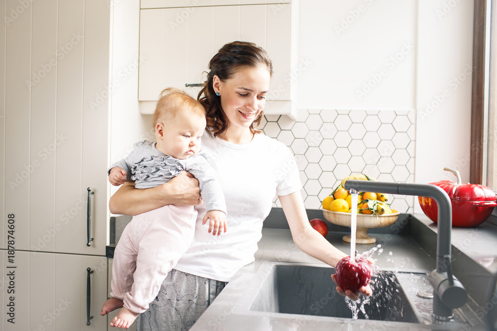 Mother washing pepper while holding a baby Mother washing pepper while holding a baby