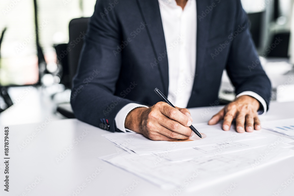 Close-up of businessman with documents at desk in office Close-up of businessman with documents at desk in office