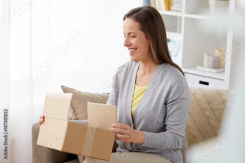 smiling woman opening parcel box at home