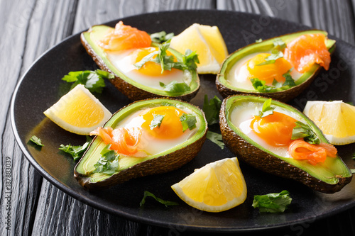 Freshly baked avocado with a homemade egg, smoked salmon and greens close-up. horizontal