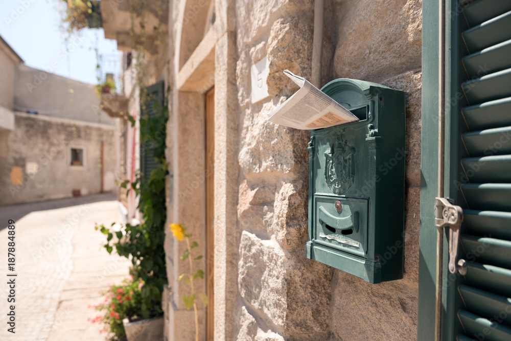 Newspaper inserted into a mailbox on the wall of the house during sunny summer day. Newspaper inserted into a mailbox on the wall of the house during sunny summer day.