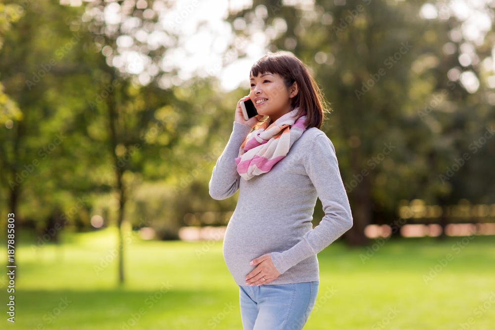 pregnant asian woman calling on smartphone at park pregnant asian woman calling on smartphone at park