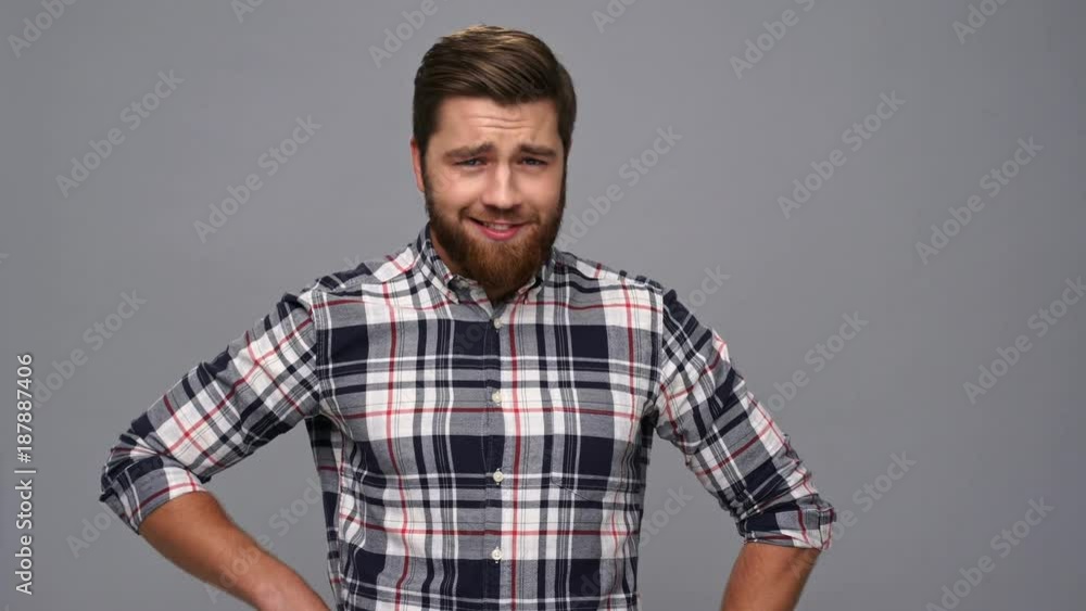 Funny cool bearded man in shirt posing and looking at the camera over gray background Funny cool bearded man in shirt posing and looking at the camera over gray background