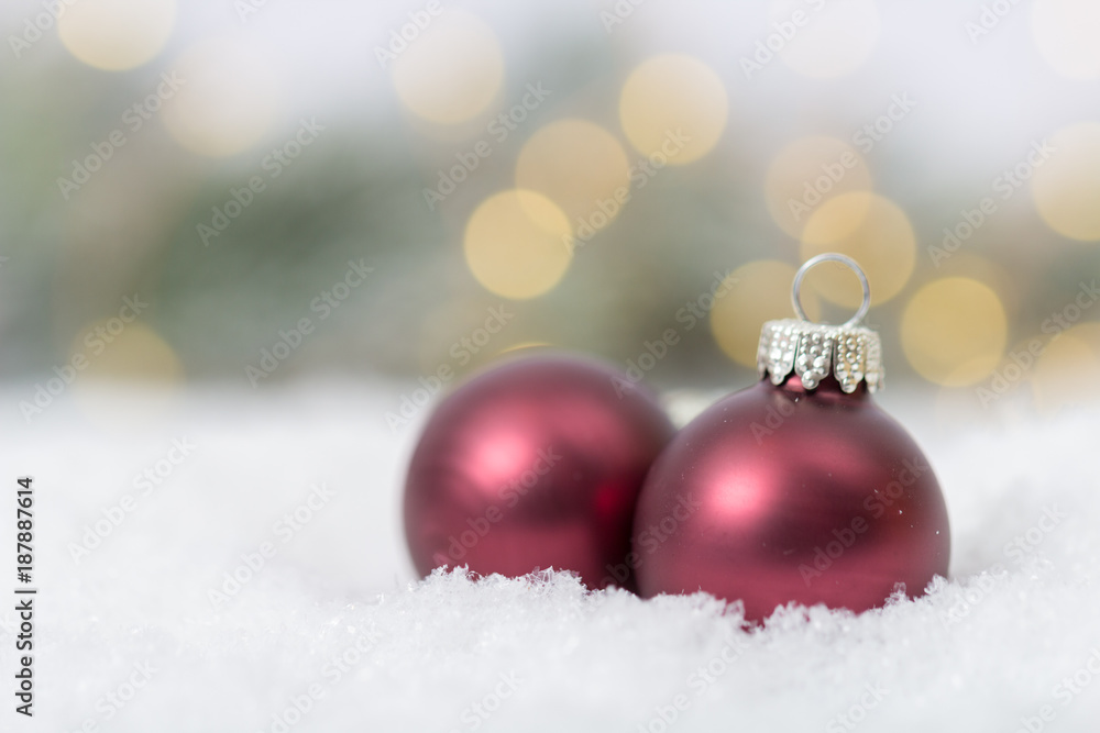 roter Christbaumschmuck vor Tannen im Schnee roter Christbaumschmuck vor Tannen im Schnee