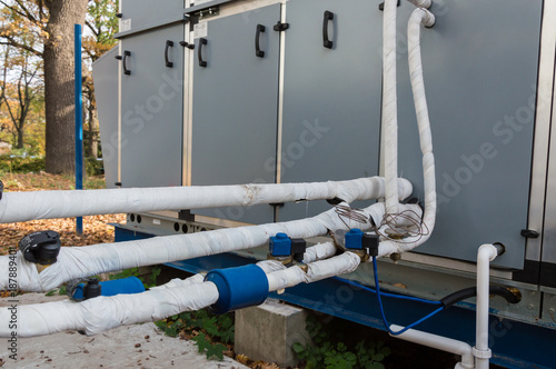 Close-up view of the insulated refrigerant pipelines with thermal expansion valves and automation sensors connected to the industrial air handling unit