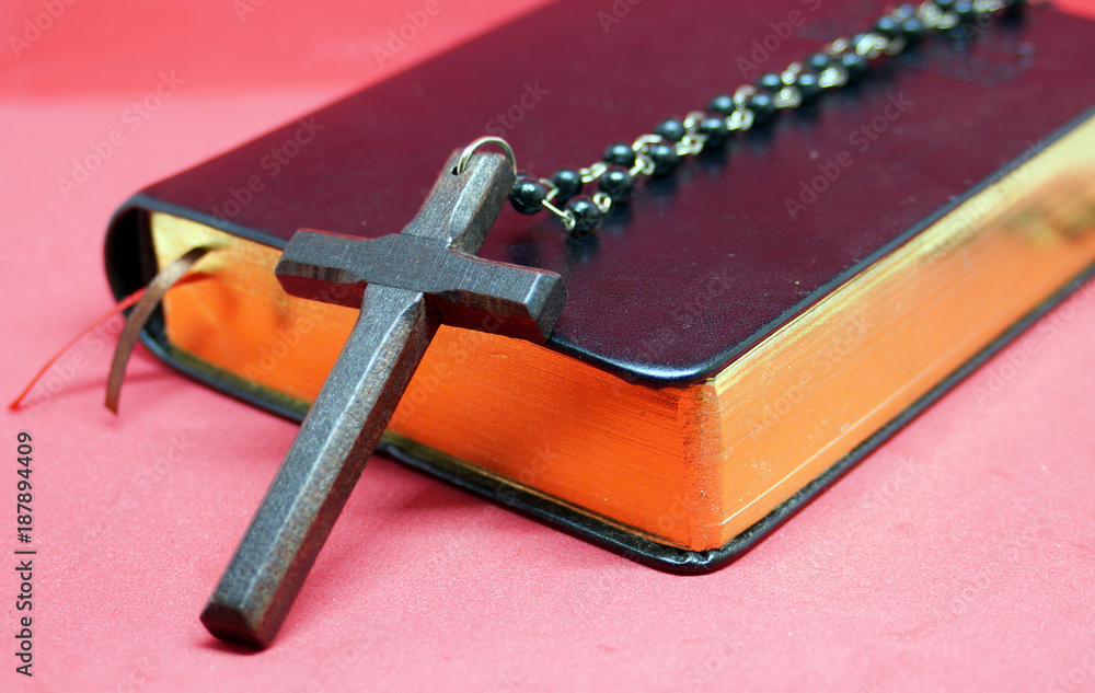 Black wooden cross with chains on bible book.