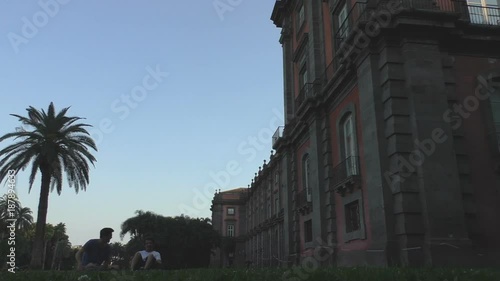 Two friends relaxing underneath a palm tree inside Capodimonte Park in Naples. photo