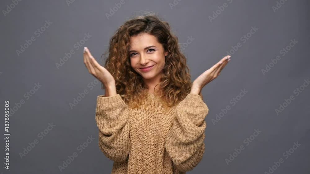 Happy curly woman in sweater covering and open her face while showing grimaces over purple background Happy curly woman in sweater covering and open her face while showing grimaces over purple background