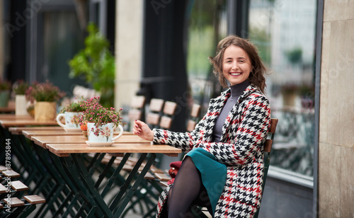 Photography Outdoor portrait of a young attractive brunette woman is sitting at terrace in a cafe on the street of Budapest