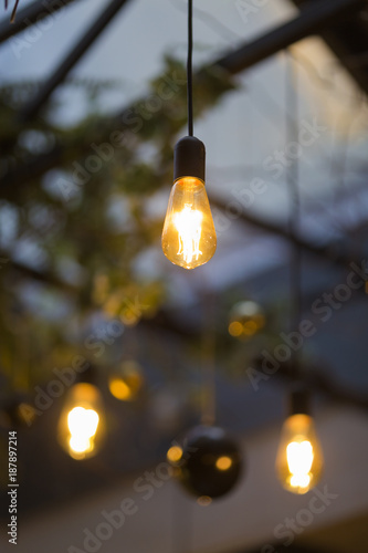 Old style electric bulbs and Christmas tree balls hanged on blurred background with focus on the foreground bulb
