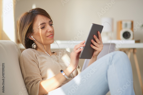 Woman sitting on sofa and using tablet.