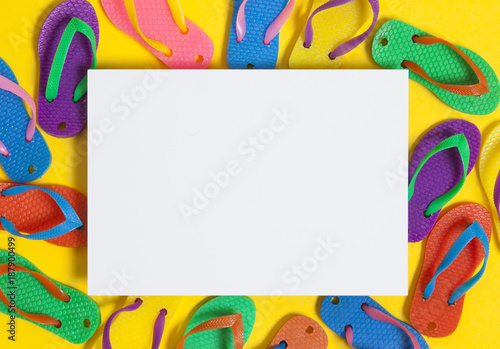 Summer flip flop sandals with a blank white sign on a bright yellow background