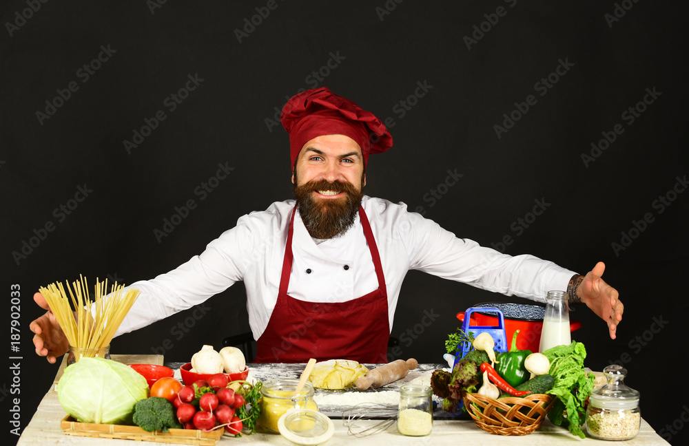 Cook with smile in burgundy uniform near ingredients.