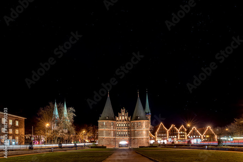 LUBECK, GERMANY - JANUARY 8, 2018: Holstentor gate and more during night with the zodiac sign Orion in the sky. Lubeck is a city in Schleswig-Holstein region. Its old town is on a UNESCO World Heritag