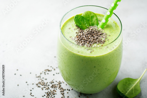 Vegetarian healthy green smoothie from avocado, spinach leaves, apple and chia seeds on gray concrete background. Selective focus. Space for text.