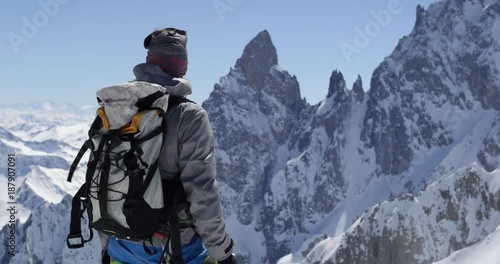 Climber mountaineer man reaching snowy mount top with ice axe in sunny day.Mountaineering ski activity. Skier people winter snow sport in alpine mountain outdoor.Back view.Slow motion 60p 4k video
