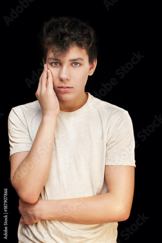 A sad boy who has a toothache on a black background