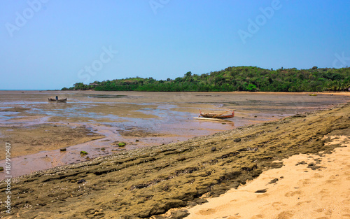 View of coastline on Nosy Komba Island lined with palm trees and boats floating in the sea, Nosy Komba, Madagascar photo