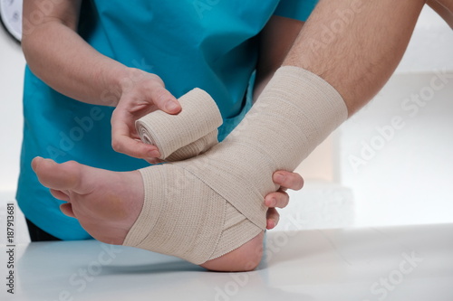 Close-up of male doctor bandaging foot of female patient
