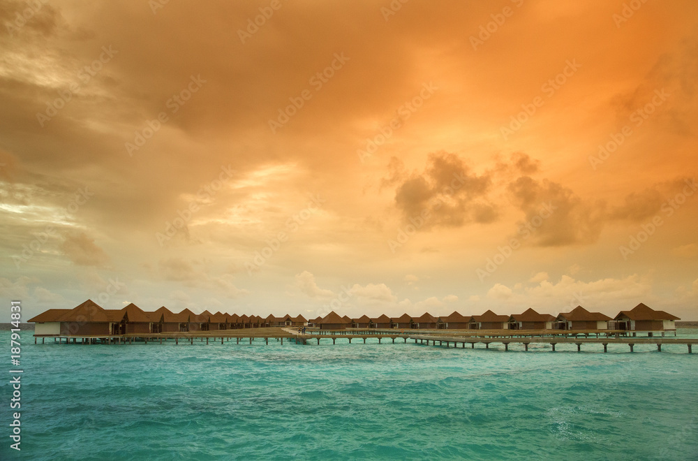 colored orange sunset in sky above sea hotel on Maldives island