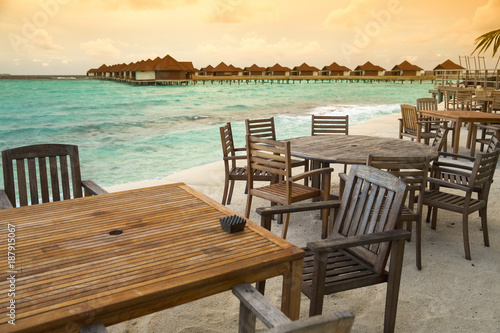 wooden tables and chairs in restaurant on Maldives island with sunset view point © sergejson