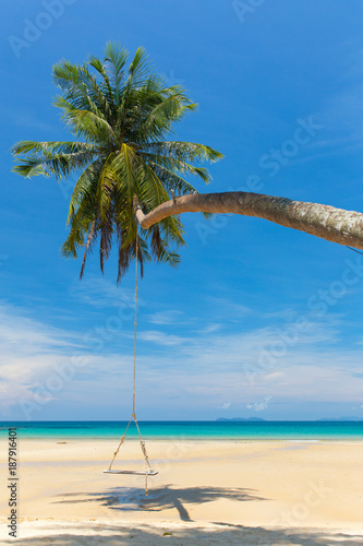 Wooden swing hanging on the beach on tropical island.