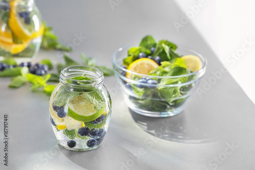 Jar of infused water and bowl with fruits on table