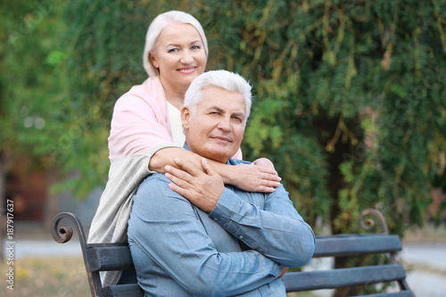 Mature couple sitting on bench outdoors
