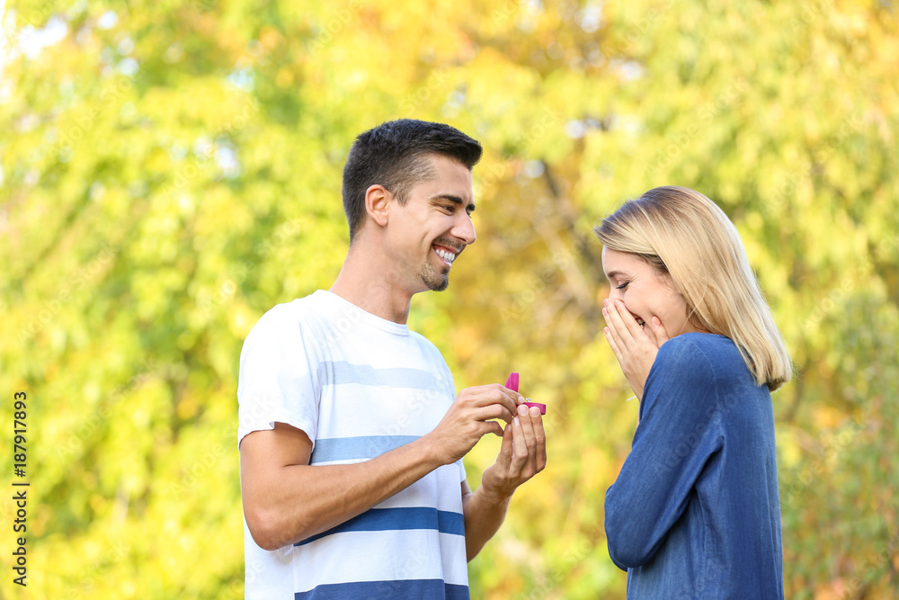 Young man with engagement ring making proposal of marriage to his girlfriend in park Young man with engagement ring making proposal of marriage to his girlfriend in park