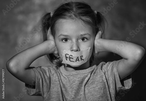 Sad little girl with taped mouth and word 