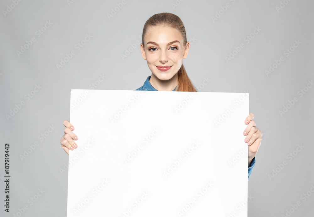 Young woman with blank advertising board on grey background Young woman with blank advertising board on grey background
