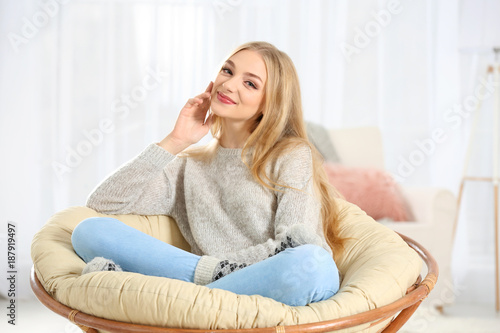 Young beautiful smiling woman relaxing  in lounge chair at home