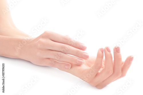 Young woman touching her hand and feeling moisturizing effect of cream on white background © Africa Studio